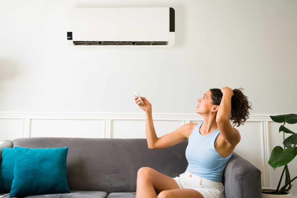 Woman using remote to adjust air conditioner.
