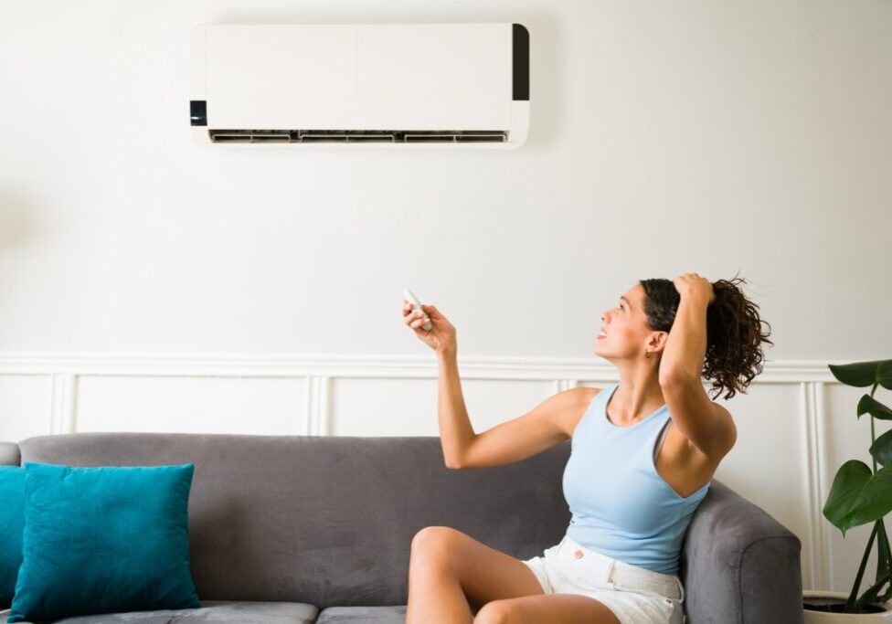 Woman using remote to adjust air conditioner.